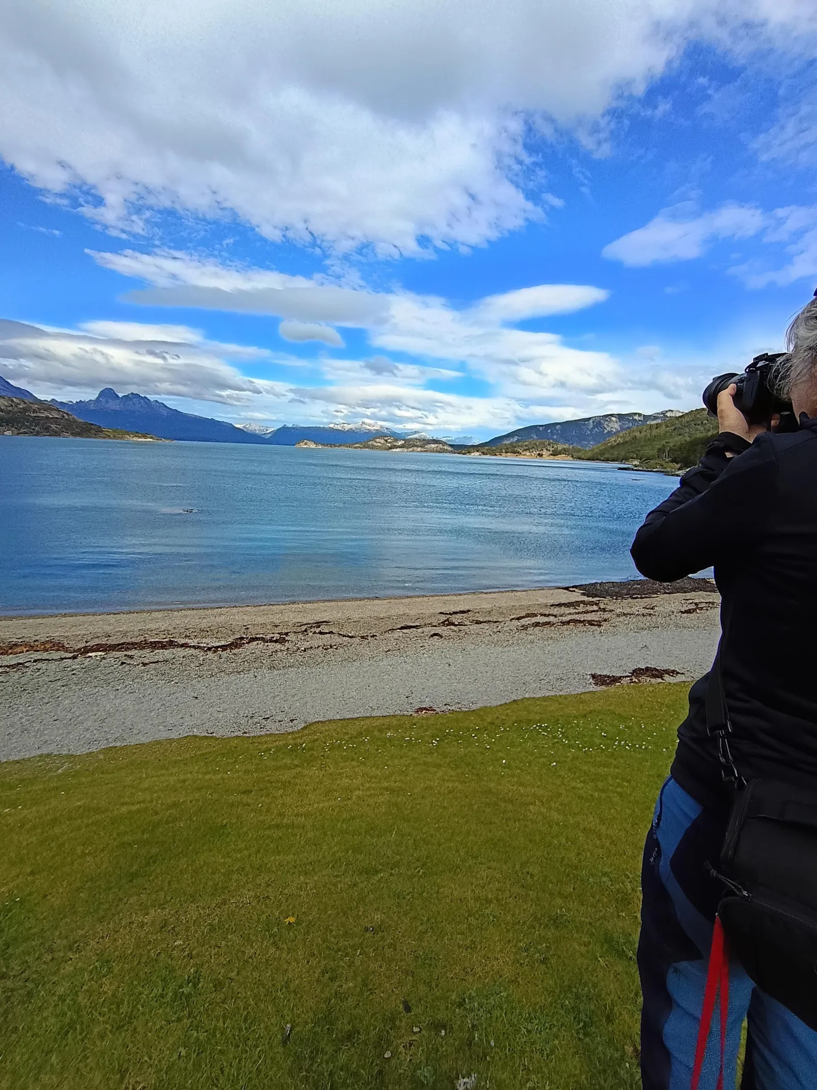 Visitor photographing the shoreline of a calm bay