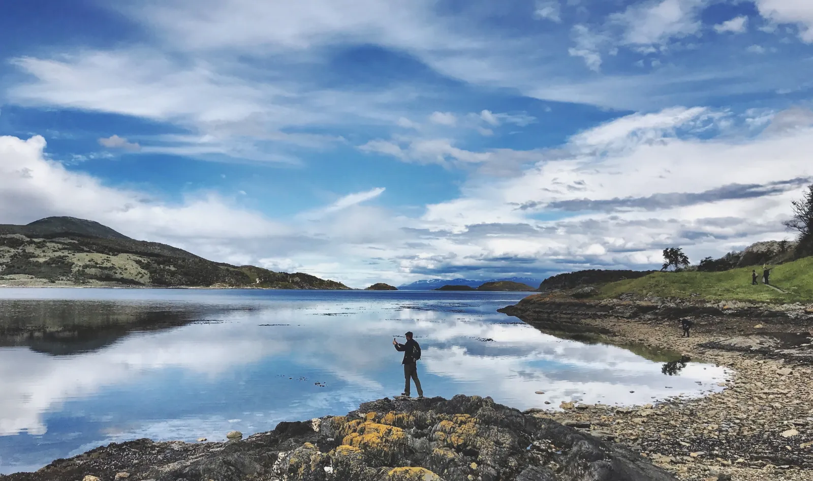 Visitor on a rock above water mirroring the clouds