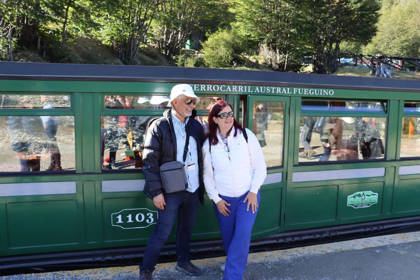 Couple beside a green carriage of the Ferrocarril Austral Fueguino