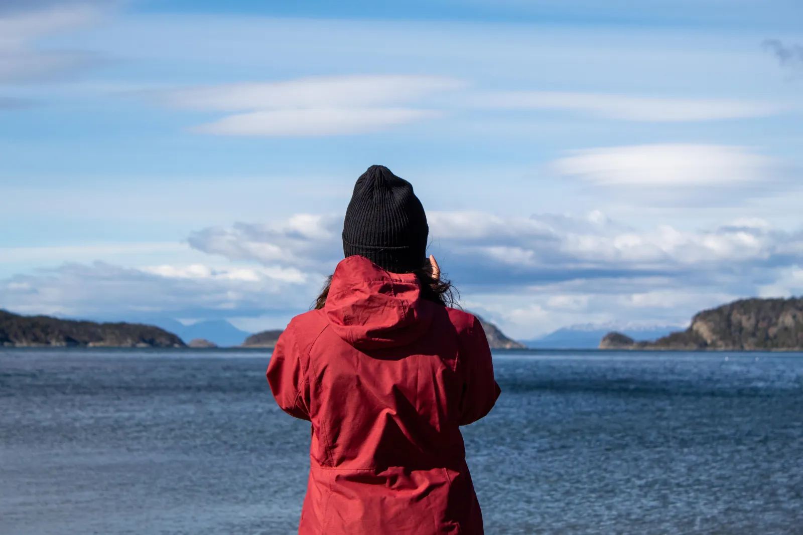 Visitor in a red jacket looking across the Beagle Channel from the park shore