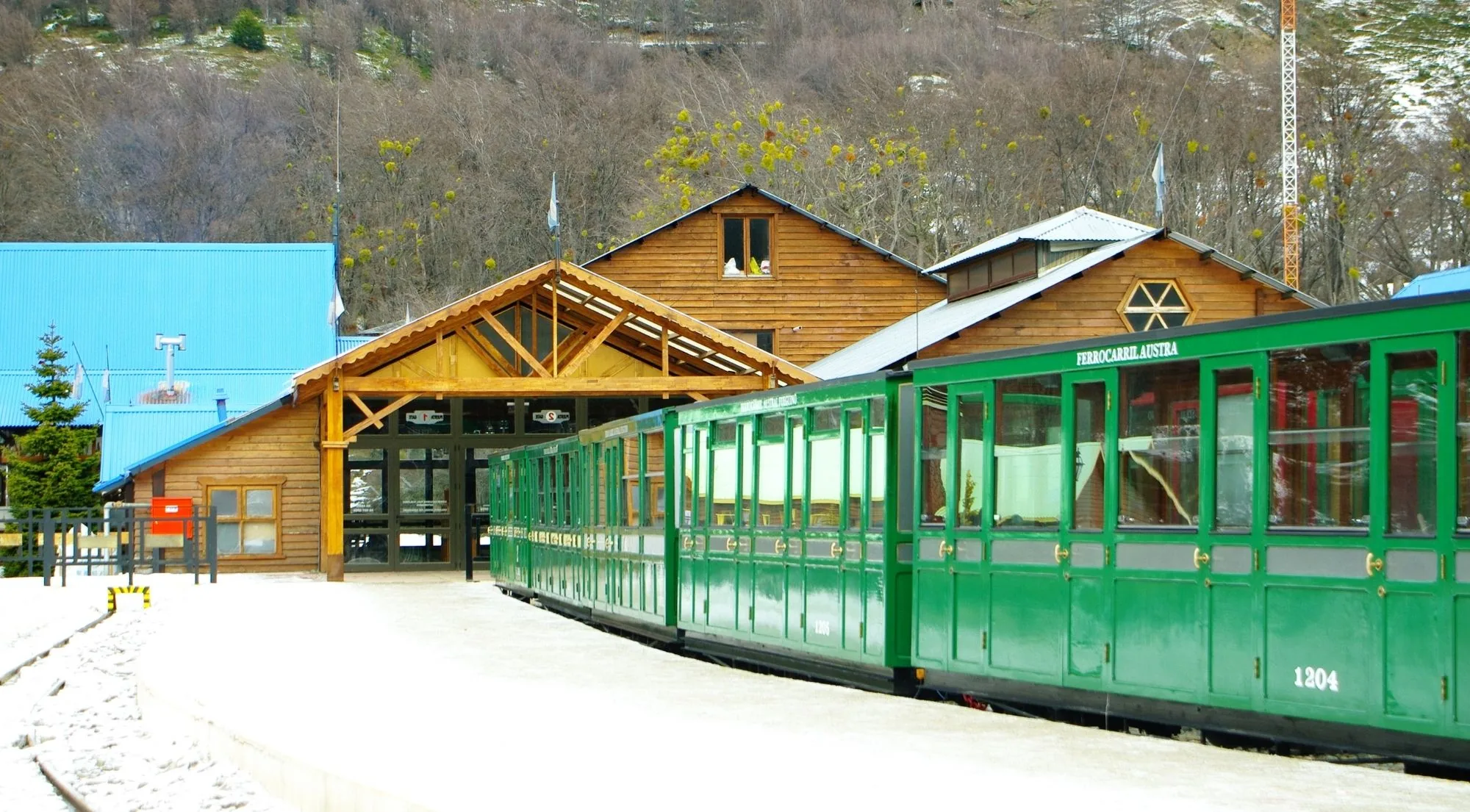 Timber station building and green train carriages in winter