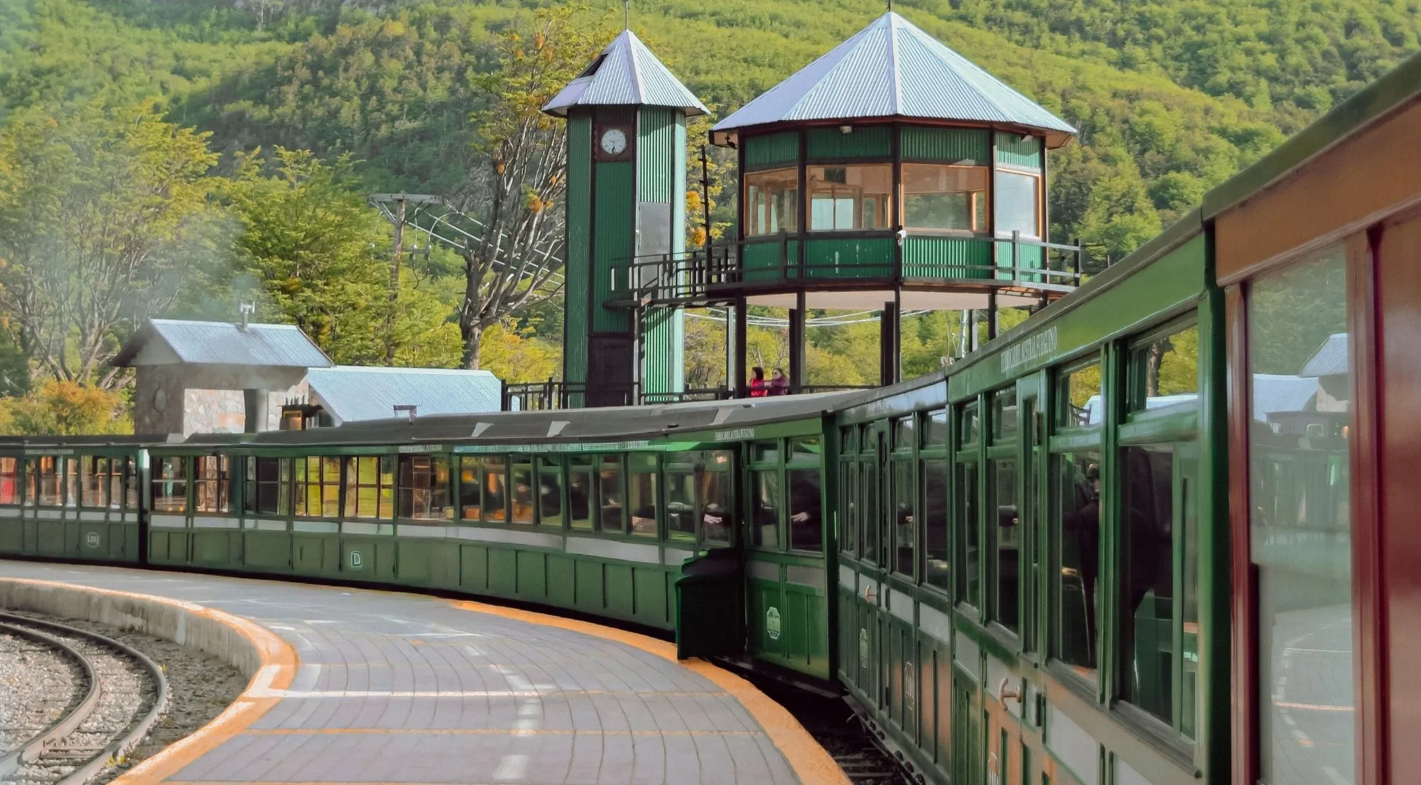 Green carriages curving along the platform at the End of the World Station
