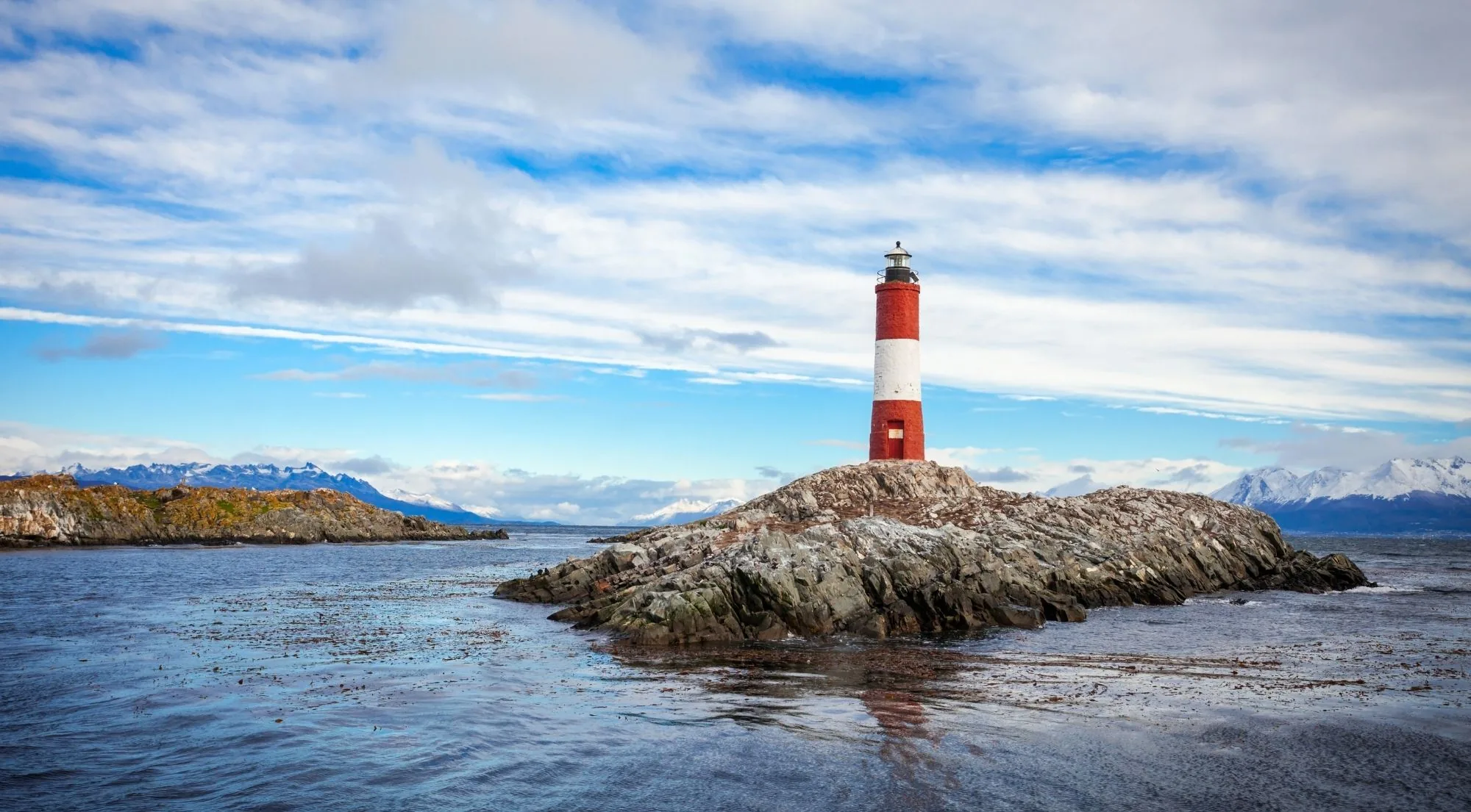 Red and white Les Éclaireurs Lighthouse on a rocky islet in the Beagle Channel
