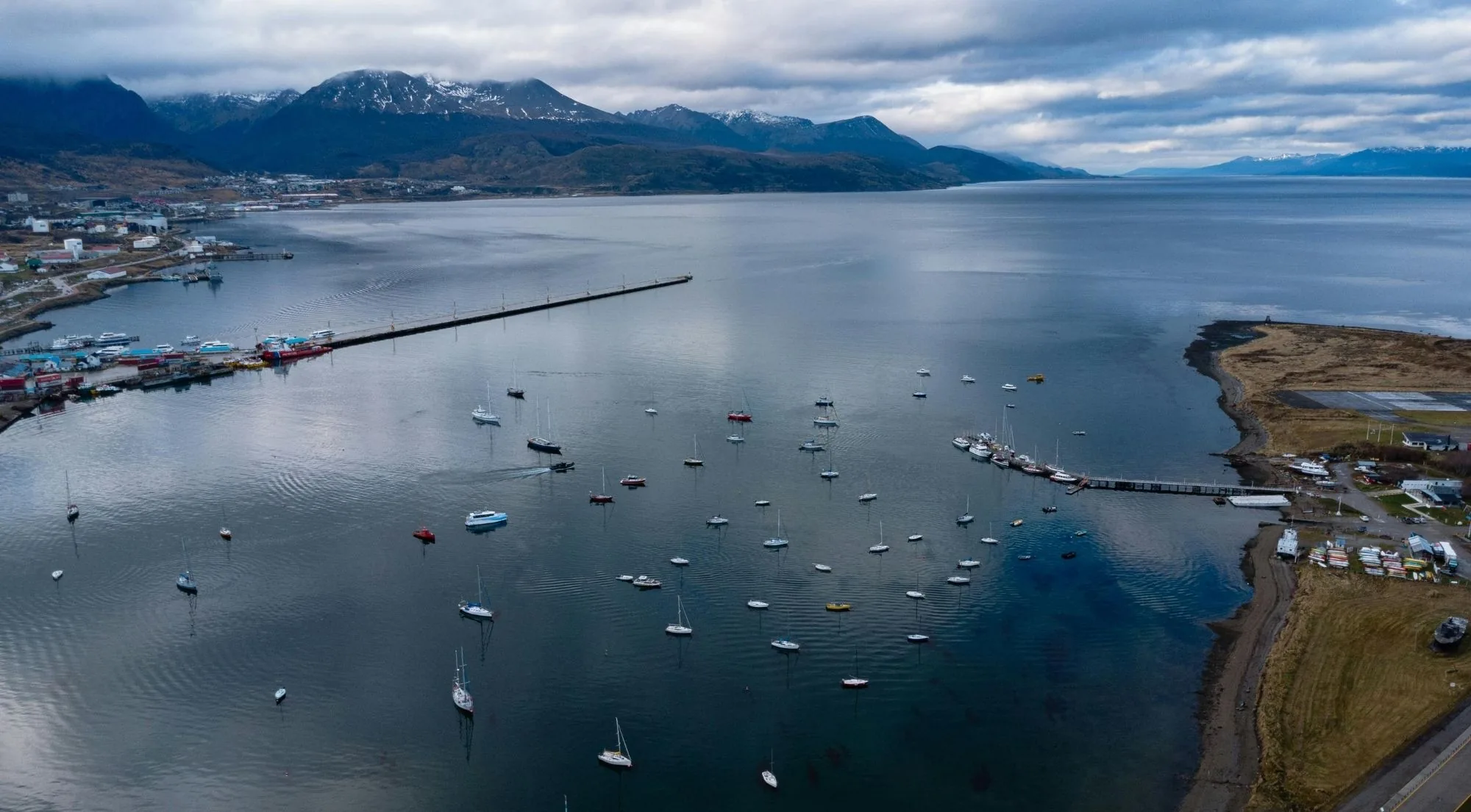 Aerial view of Ushuaia bay and its moored sailboats with mountains beyond